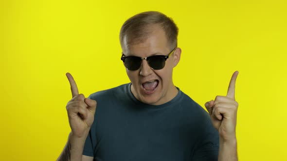 Portrait of Young Man Posing in T-shirt. Cool Handsome Guy Wears Sunglasses, Point Fingers at Camera