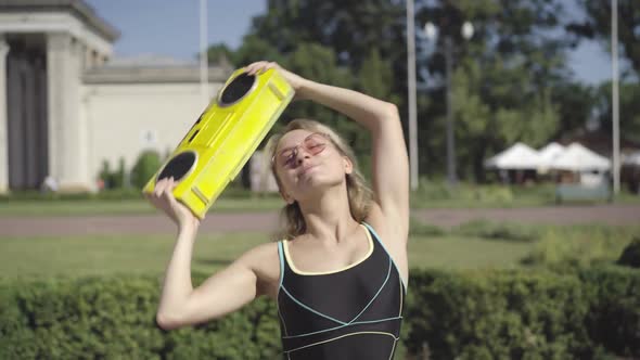 Carefree Happy 1980s Woman Dancing Slowly and Signing To Disco Music Holding Retro Yellow Tape