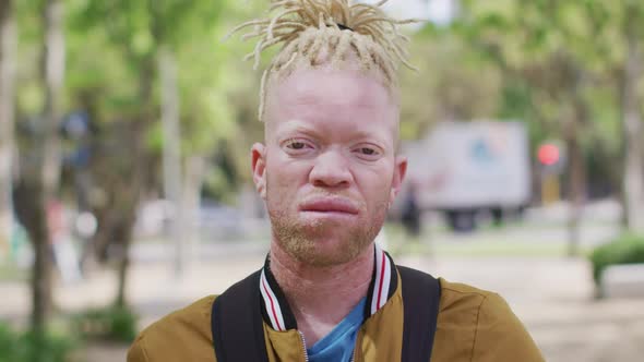 Portrait of albino african american man with dreadlocks in park looking at camera