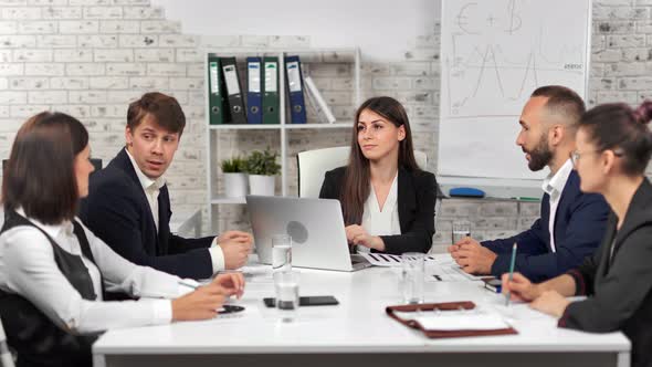 Female Teamleader Discussing Business Project with Employee Sitting on Desk at Modern Office
