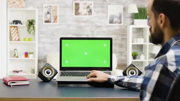 Man Looking at Modern Laptop with Green Screen