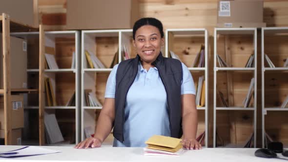 Happy Female Postal Service Clerk Smiling behind Counter