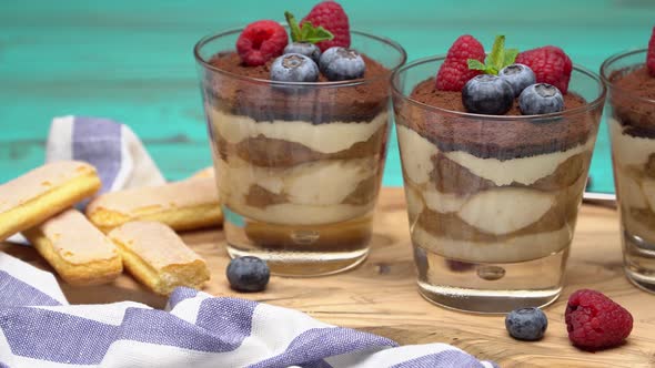 Classic Tiramisu Dessert with Blueberries and Strawberries in a Glass Cup and Savoiardi Cookies