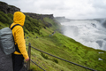Man tourist with backpack and green jacket visit Gullfoss powerful famous waterfall in Iceland - PhotoDune Item for Sale