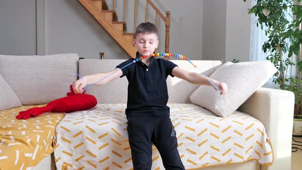 boy playing and spinning colored wooden beads on a string, rope on bed