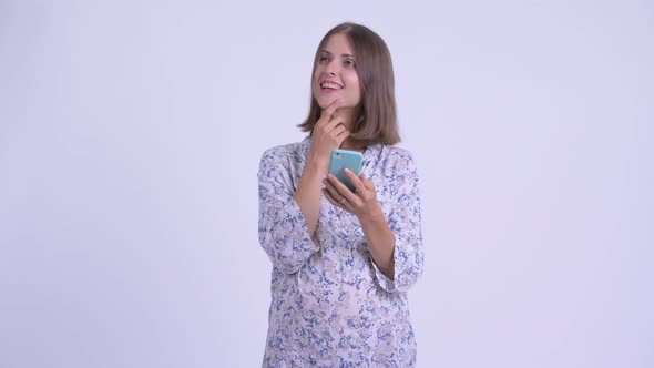 Happy Young Pregnant Woman Thinking While Using Phone