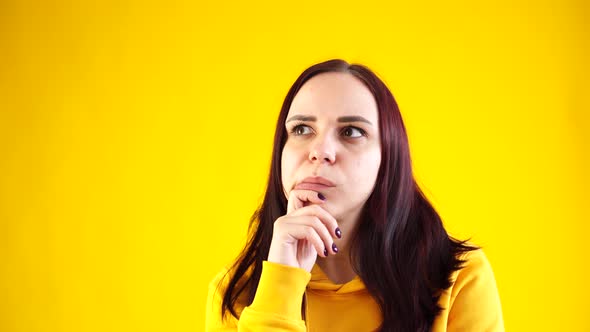 Close Up of Young Woman Scratching Thoughtfully Her Chin on Yellow Background