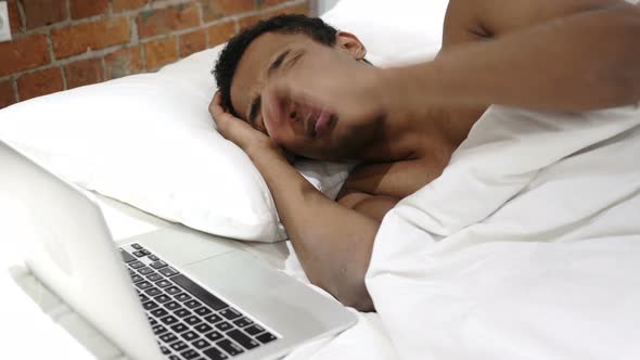 African Man in Bed Reacting to Loss and Failure on Laptop