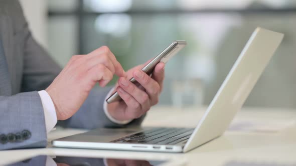 Close Up of Businessman Using Smartphone Near Laptop