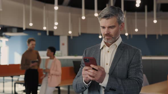 Successful Businessman in Formal Wear Usin Smartphone Standing at the Moders Office