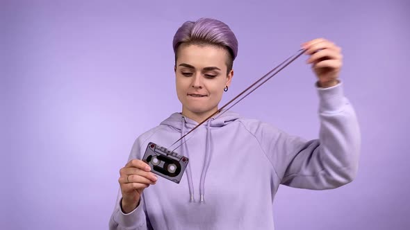 Young Woman Holding Vintage Audiocassette Pulling Magnetic Tape Out