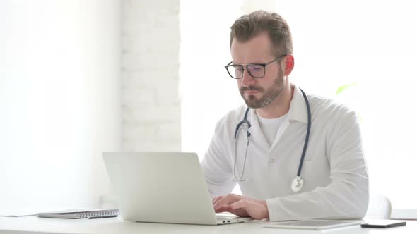 Doctor Shaking Head As No Sign While Using Laptop in Office