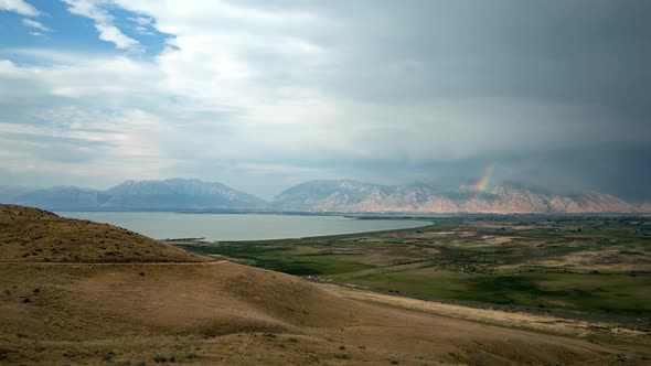 Time lapse over grassy hills towards lake and mountains