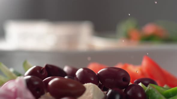 Camera follows putting dressing over greek salad. Slow Motion.