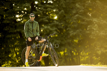 Young man with ebike, mountain bike with electric battery in the park