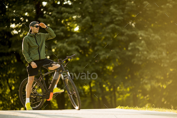 Young man with ebike, mountain bike with electric battery in the park