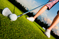 closeup shot of golf ball with golf club right before tee off with player legs in background - PhotoDune Item for Sale