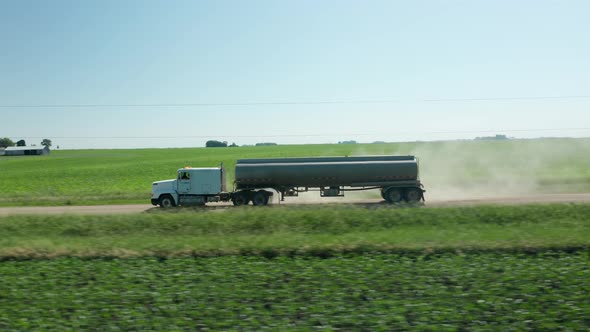 Aerial side view, fuel truck driving on rural countryside farm land dirt road. Series