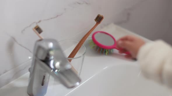 Mother and Her Daughter Taking Toothbrushes From a Glass Before Brushing your Teeth in the Bathroom