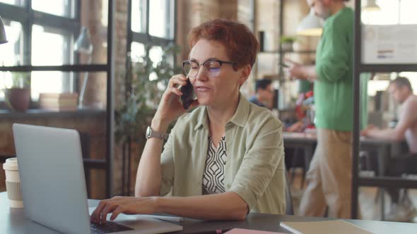 Businesswoman Working on Laptop and Speaking on Phone