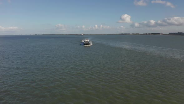 Drone flying past long cargo ship with a city in the background