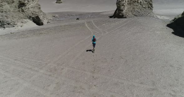 Aerial footage of woman trail runner cross country running  on sand desert dunes