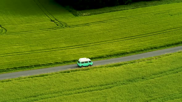 Mini Bus Driving On Narrow Country Road, With Green Fields On Both Sides, Drone Stock Footage 6