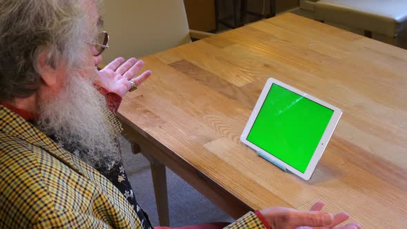 elderly man using a tablet device, talking to green screen concept shot