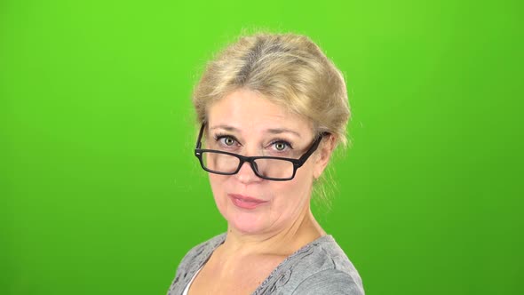 Woman Smiles and Drops Her Glasses at the Eyes. Green Screen