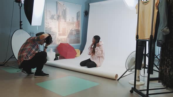 Backstage of the Photo Shoot: Black Model Sitting on the Floor and Posing for a Photographer