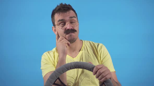 Portrait Thoughtful Male Freak with Mustache Driving a Car on a Blue Background Isolate