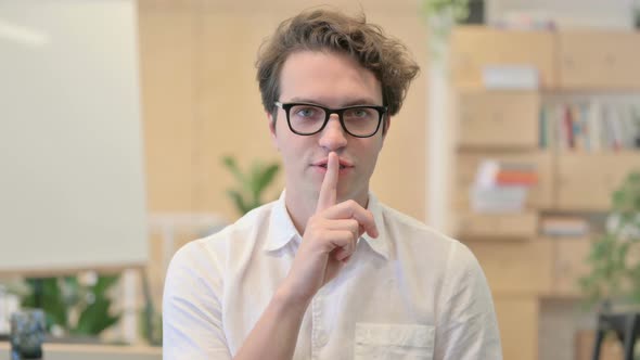 Portrait of Young Man Showing Quiet Sign By Finger on Lips