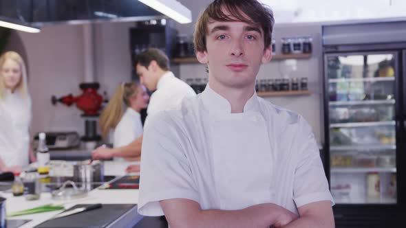Caucasian male cook working in a restaurant kitchen, smiling to the camera