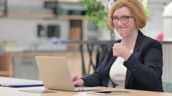 Appreciative Old Businesswoman with Laptop Doing Thumbs Up