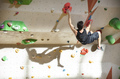 Caucasian young man bouldering in indoor climbing gym. - PhotoDune Item for Sale