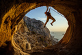 Young woman climbing challenging route in cave with beautiful sea view in background - PhotoDune Item for Sale