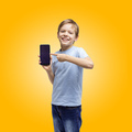 Cute young boy holding and pointing at smart phone, over yellow background. - PhotoDune Item for Sale