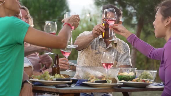 Handsome Hispanic Man Toasting Glass of Wine with Friends During Summer Dinner in the Garden