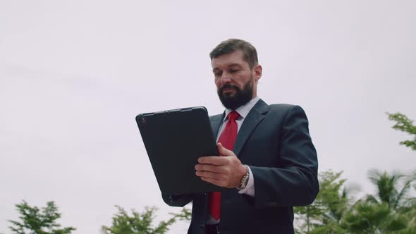 Portrait of a Serious Business Man Bearded Businessman in an Expensive Suit in a Red Tie Working on