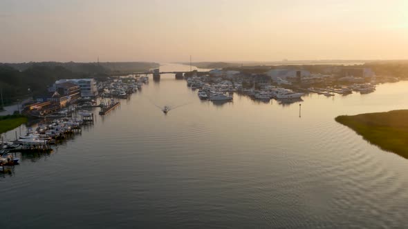 4k view of small beach town at sunrise over the water way revealing boats and green marsh early in t