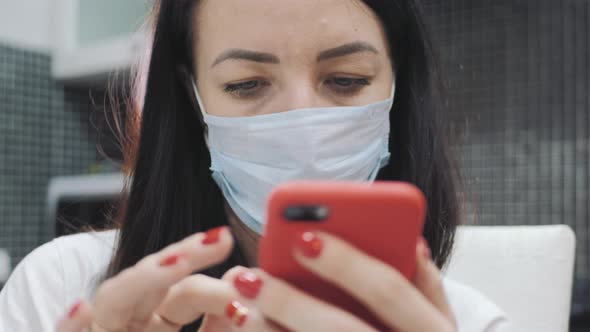 Young Woman Wearing Face Mask Using Mobile Phone Reading Information About Coronavirus Disease 2019