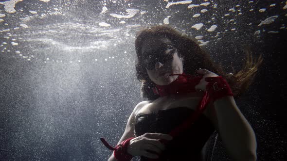 Sexy Lady with Red Whip Is Swimming Underwater in Bubbles and Light Mysterious and Magic Shot