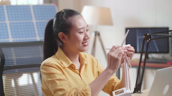 Close Up Of Asian Woman Assemble The Wind Turbine While Working With Laptop Next To The Solar Cell