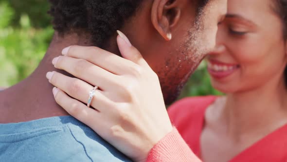 Close up of happy biracial woman with engagement ring on hand hugging to fiance