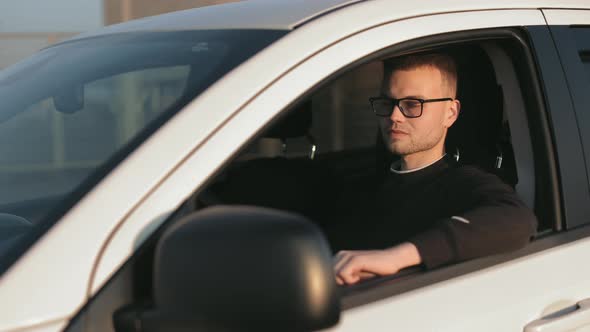 A Happy Man is Sitting in a Car and Holding His Hand on the Door