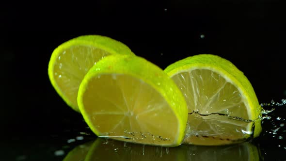 Super Slow Motion Shot of Fresh Lime Slices Falling Into Water Isolated on Black at 1000 Fps