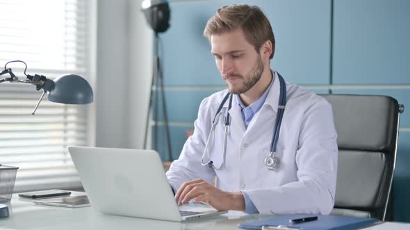 Doctor with Laptop Smiling at the Camera in Clinic