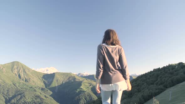 Back View of Young Woman Hiking Away in Mountain Outdoor Nature Scenery During Sunny Summer Day