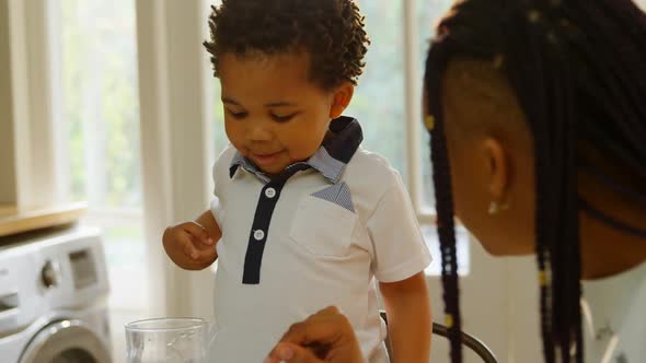 Close-up of young black mother and son sitting at dining table in kitchen of comfortable home 4k