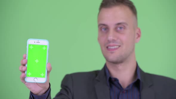 Face of Happy Handsome Businessman in Suit Showing Phone